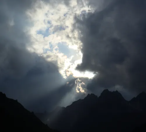 Dunkler Himmel mit einzelnen Sonnenstrahlen über Bergspitzen