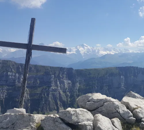 Kreuz auf Berg mit Aussicht auf Bergkette